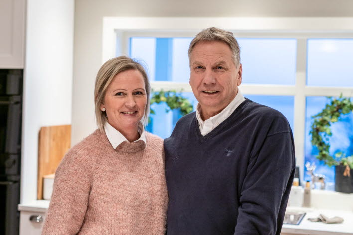 Voksent par på kjøkkenet hun i rosa genser og han med blå genser.