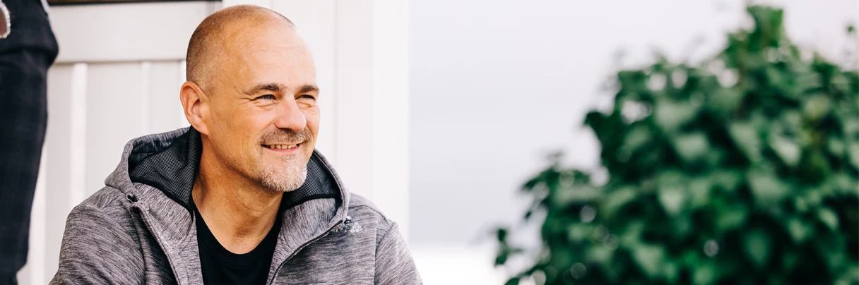 Man med skägg tittar på en person som sitter mittemot honom. 