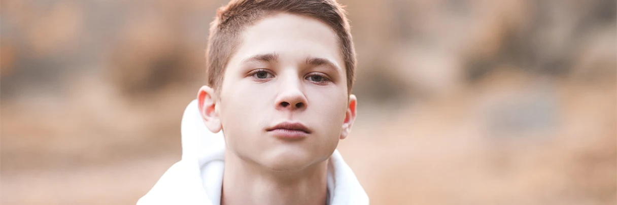 Ung gutt med hvit hettegenser, ola-jakke og kort mørkt hår