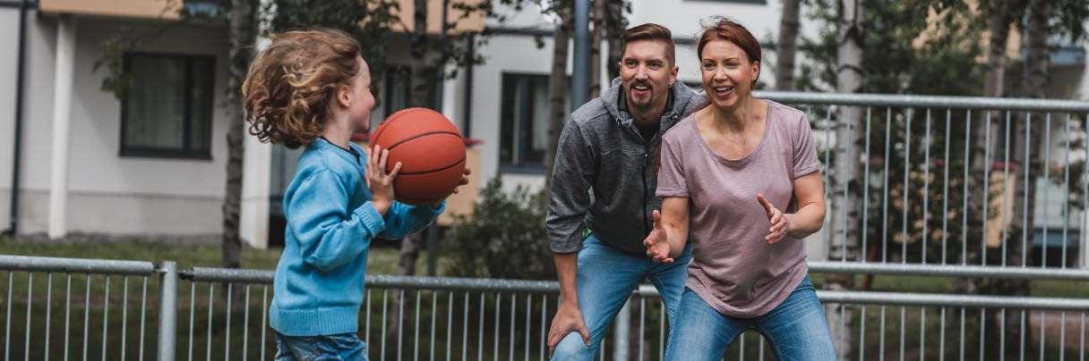två vuxna personer och ett barn spelar basket