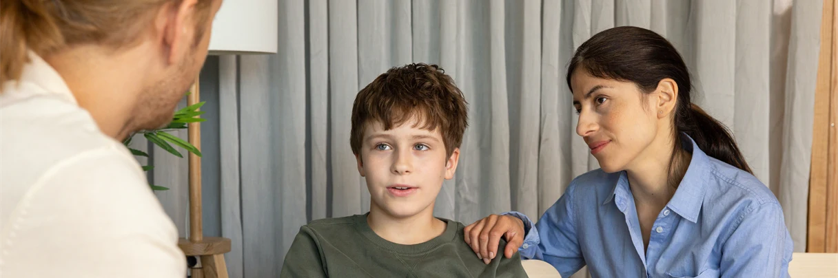 A group of people sitting at a table looking at a laptop