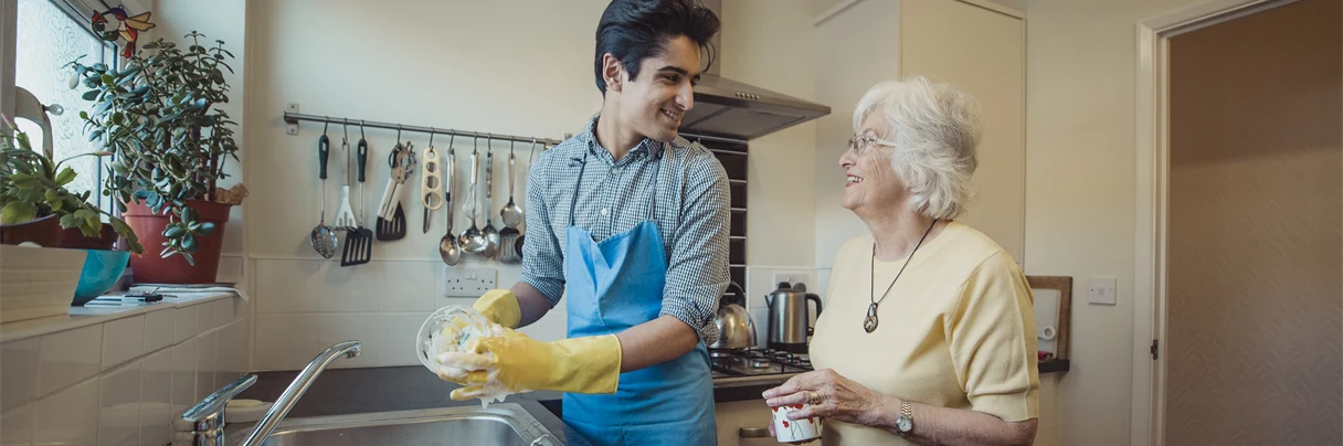 Mann vasker opp for gammel dame, de smiler til hverandre