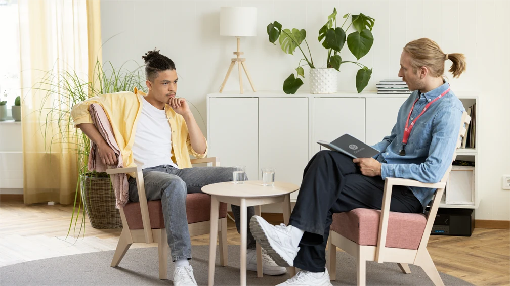 En man och en ung man sitter i två fåtöljer och samtalar
