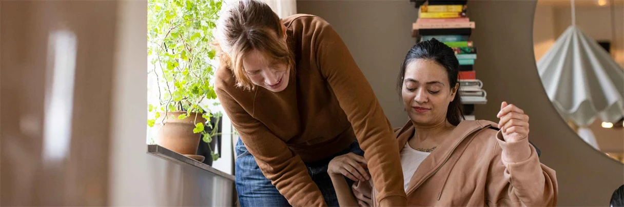 en kvinna hjälper en annan kvinna i rullstol 