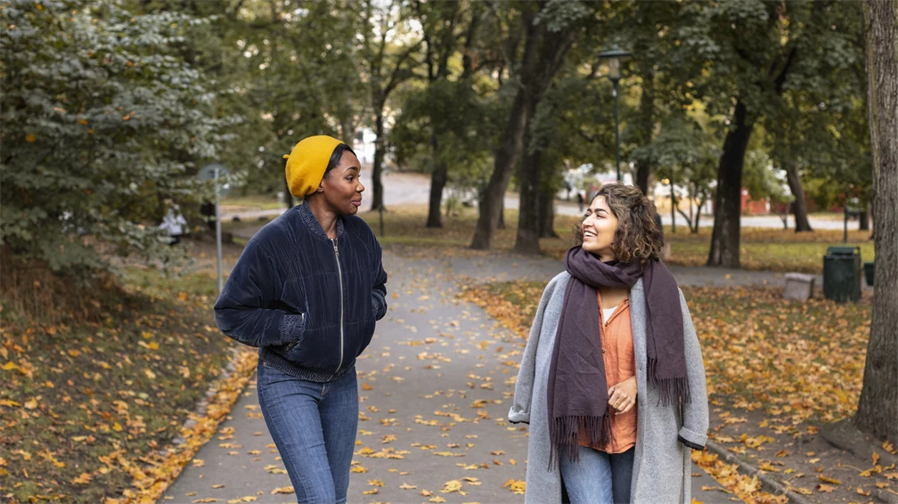 Två kvinnor går utomhus och samtalar.