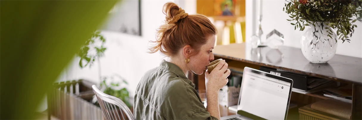 Kvinna som dricker kaffe och tittar på sin dator