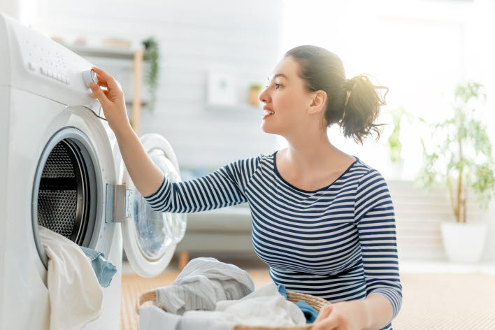 Kvinne putter klesvask i vaskemaskin