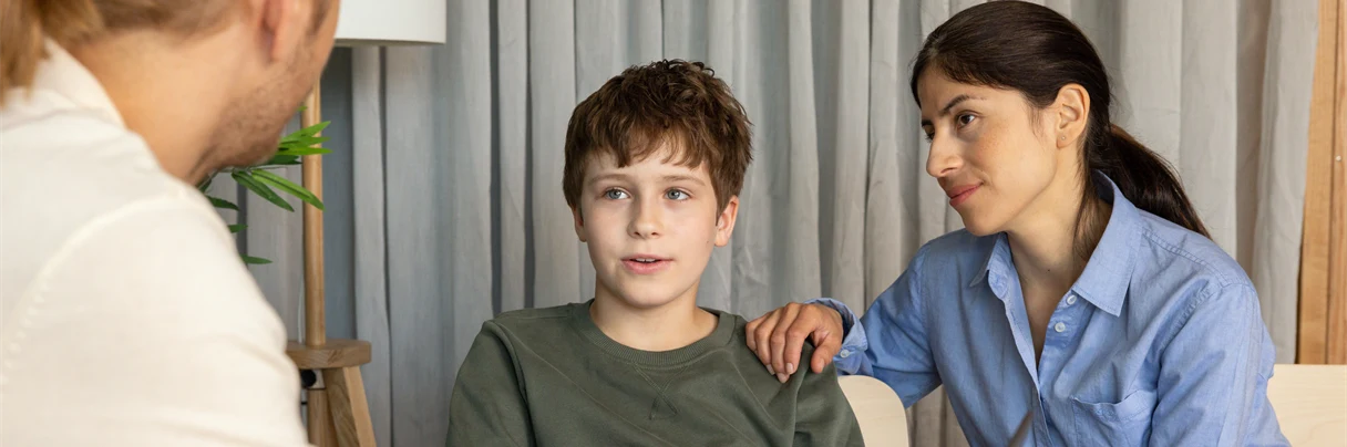 A group of people sitting at a table looking at a laptop