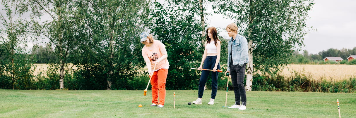 A group of young people playing croquet.