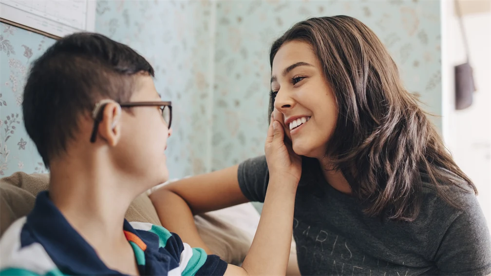 En pojke i randig tröja håller handen över en kvinnas kind. 