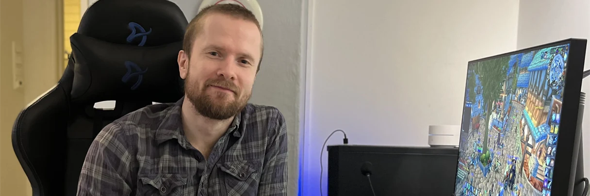 Gamingkontakt Tobias smiler til kamera foran dataskjermen sin