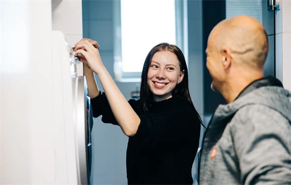 Tyttö ja työntekijä täyttävät pyykinpesukonetta