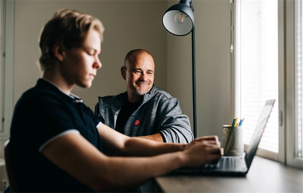 Poika ja ohjaaja tekevät yhdessä läksyjä tietokoneella