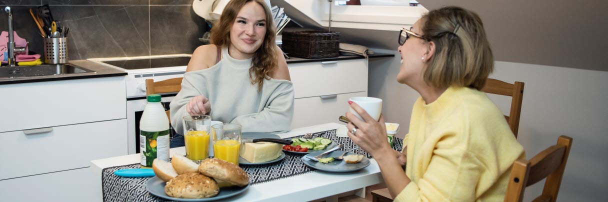Två kvinnor som sitter vid ett bort och äter frukost