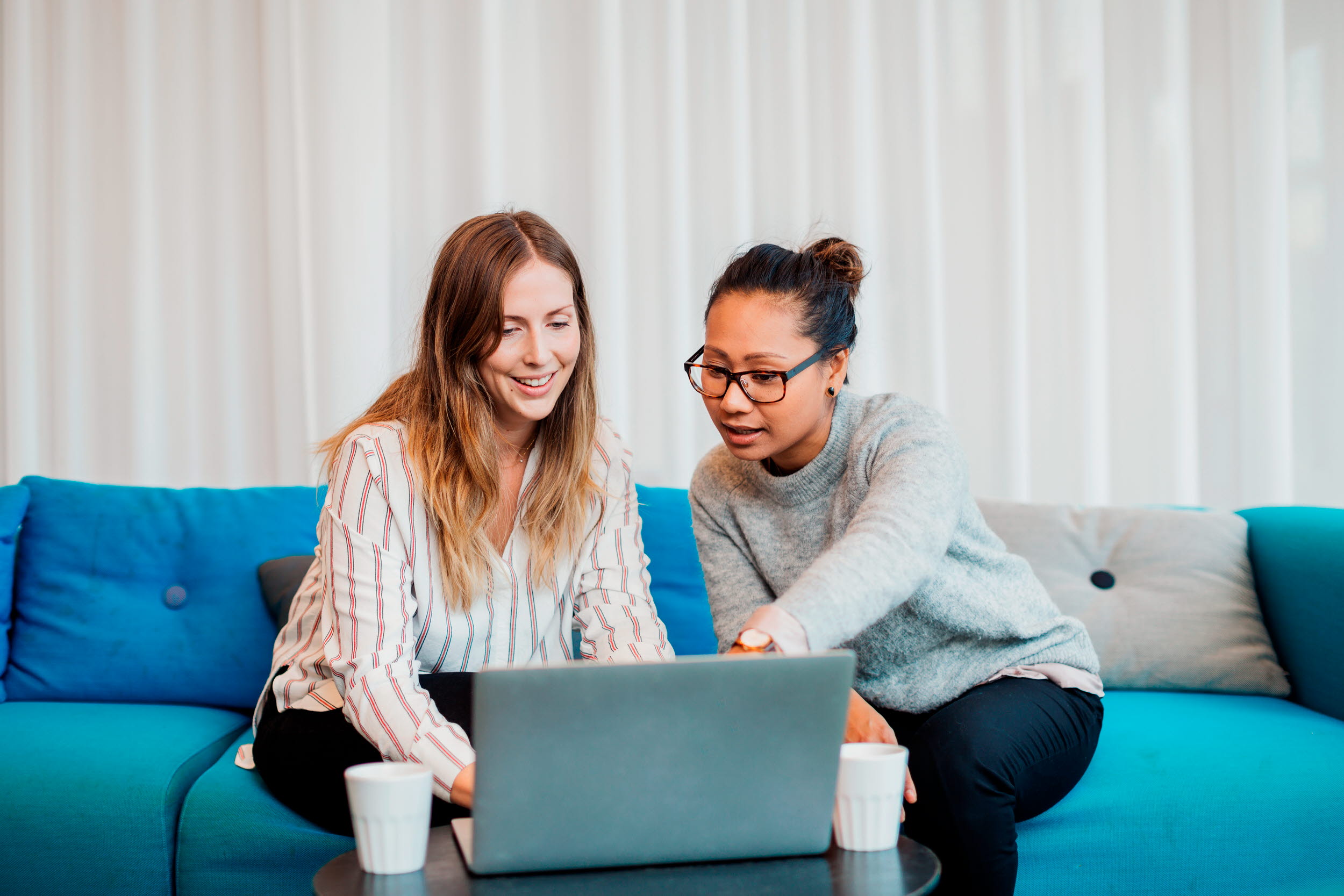 två kvinnor i en soffa som diskuterar vad som händer på datorn