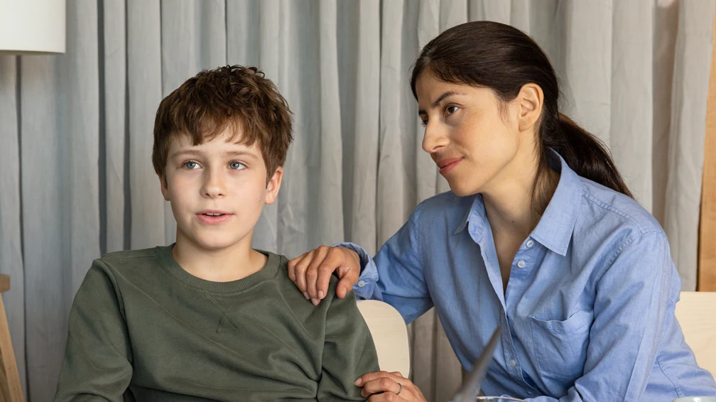 En kvinna och en man sitter med en pojke vid ett bord, på bordet