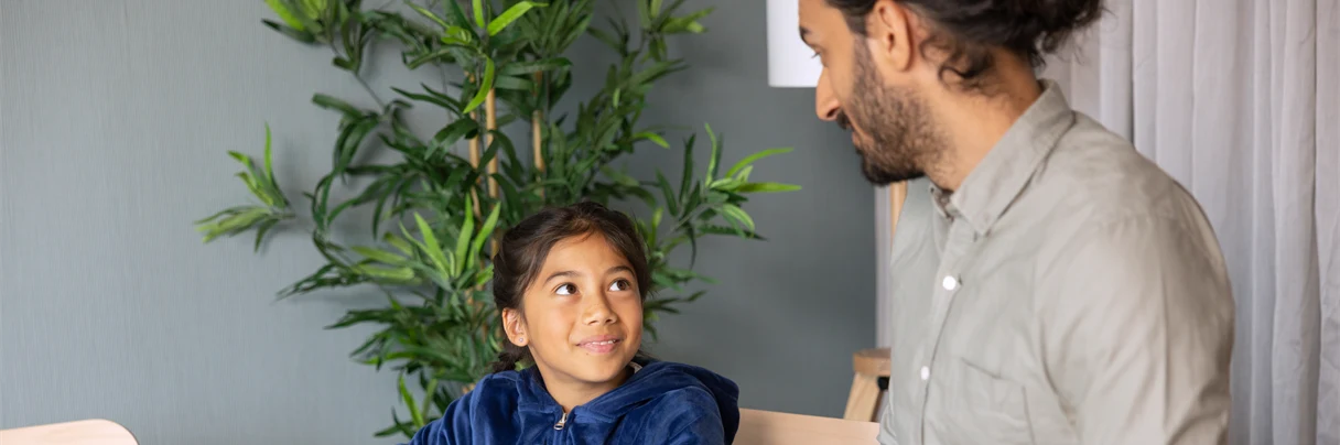 Man och flicka spelar spel, båda har mörkt hår och tittar på varandra