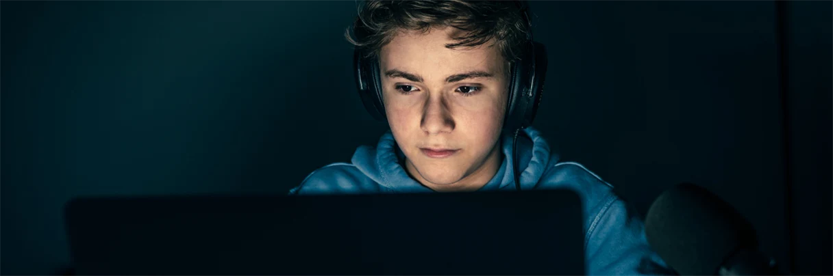 Gutt med headset sitter foran gamingskjerm