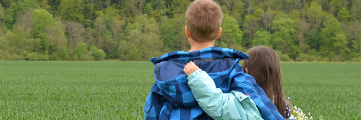 Liten gutt og jente på en eng